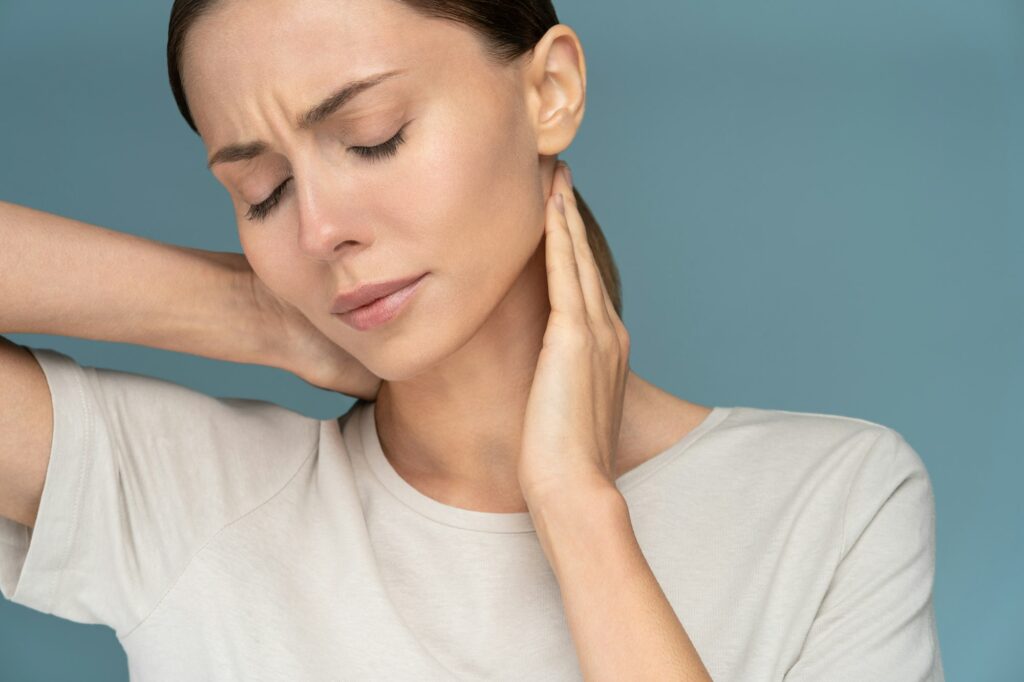 Woman suffering from chronic neck pain, gently massages with hands, having upper back ache